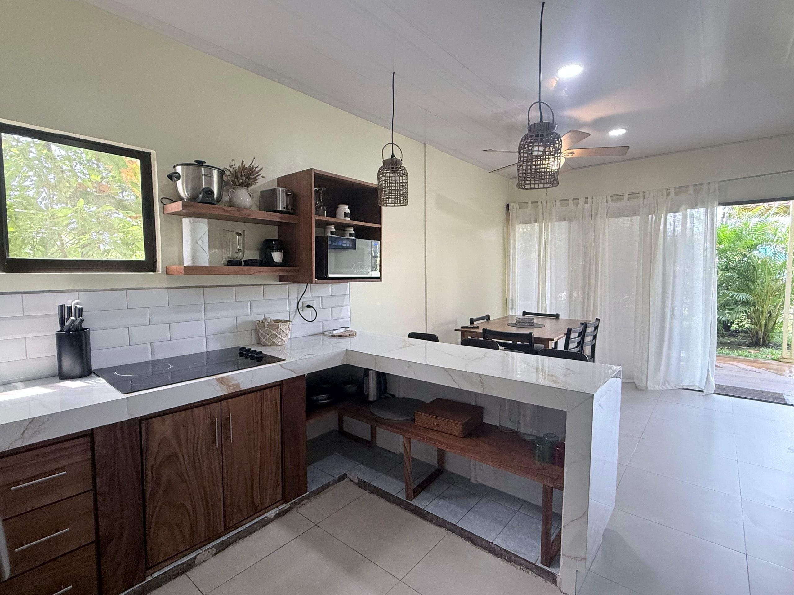 A modern kitchen with a white countertop, wooden cabinets, and a dining area with a table and chairs.