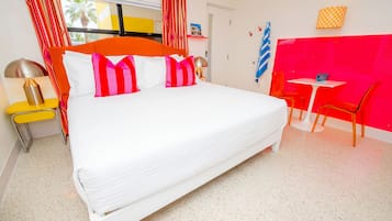 A hotel room with a large bed, a desk, and a chair.