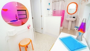 Une salle de bain équipée d’une douche, d’un lavabo, d’un miroir et d’une lampe à lave.