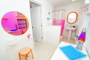 Une salle de bain équipée d’une douche, d’un lavabo, d’un miroir et d’une lampe à lave.