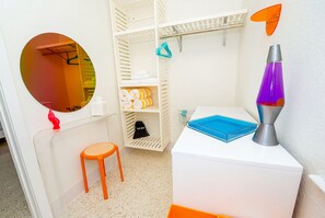 A room with a white wardrobe, a round mirror, a small orange stool, a blue tray, and a lava lamp. - King Room in Treasure Island, just steps from Sunset Beach. (Treasure Island)
