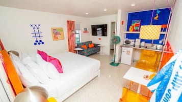 A hotel room with a bed, a sofa, a TV, a small table, and a kitchenette.