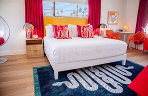Une chambre moderne avec un grand lit, une table de chevet avec une lampe, une petite table avec une lampe et une chaise.