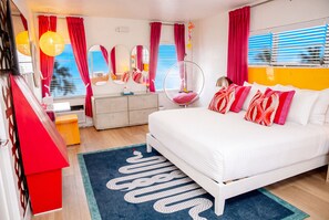 Un dormitorio moderno con cama, una silla colgante, cómoda y espejo.