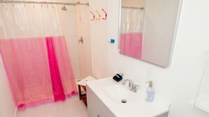 Une salle de bain équipée d’une douche, d’un lavabo, d’un miroir et de toilettes.