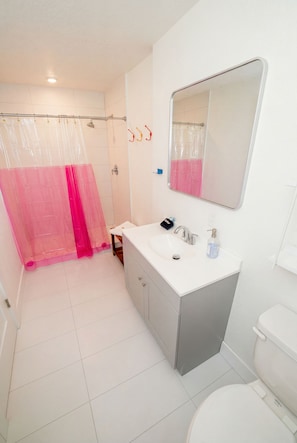 Une salle de bain équipée d’une douche, d’un lavabo, d’un miroir et de toilettes.