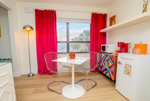 A compact kitchen with a white refrigerator, a microwave, and a colorful cabinet. - King Suite in Treasure Island, just steps from Sunset Beach. View of the Gulf from your room! (Treasure Island)