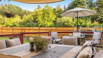 An outdoor patio with a table and chairs, a hanging flower pot, and a sign for 'The Grayson's Backyard Grill & Eatery.'