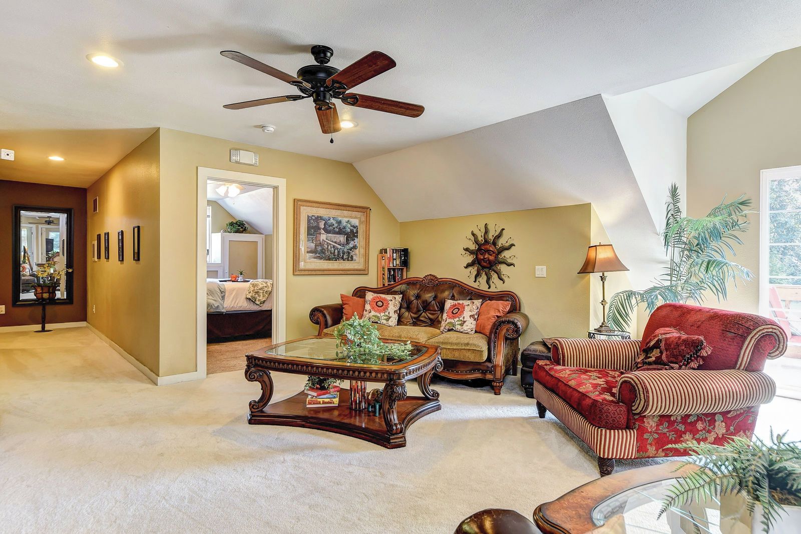 A spacious living room with a high ceiling, a ceiling fan, and a large window providing natural light.