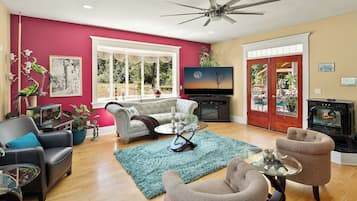 Una sala de estar con chimenea, televisor y un ventanal grande.