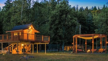 A wooden cabin with a balcony and a covered outdoor seating area.