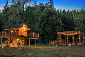 A wooden cabin with a balcony and a covered outdoor seating area.