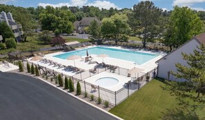 Ein rechteckiger Pool mit einer umlaufenden Liegefläche, Liegestühlen und einer kleinen, runden Whirlwanne.