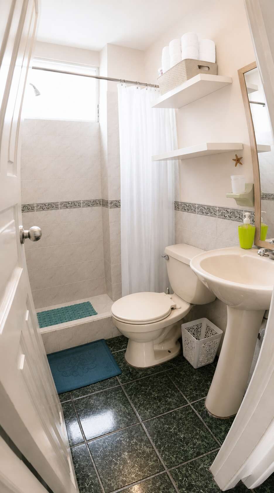 Et lille badeværelse med bruser, toilet og håndvask.