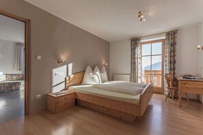 Ein Schlafzimmer mit einem hölzernen Bett, Nachttischen, einem Schreibtisch und einem Fenster mit Vorhängen.