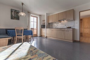 Ett modernt kök med träskåp, en matplats med bord och stolar samt ett stort fönster med gardiner.