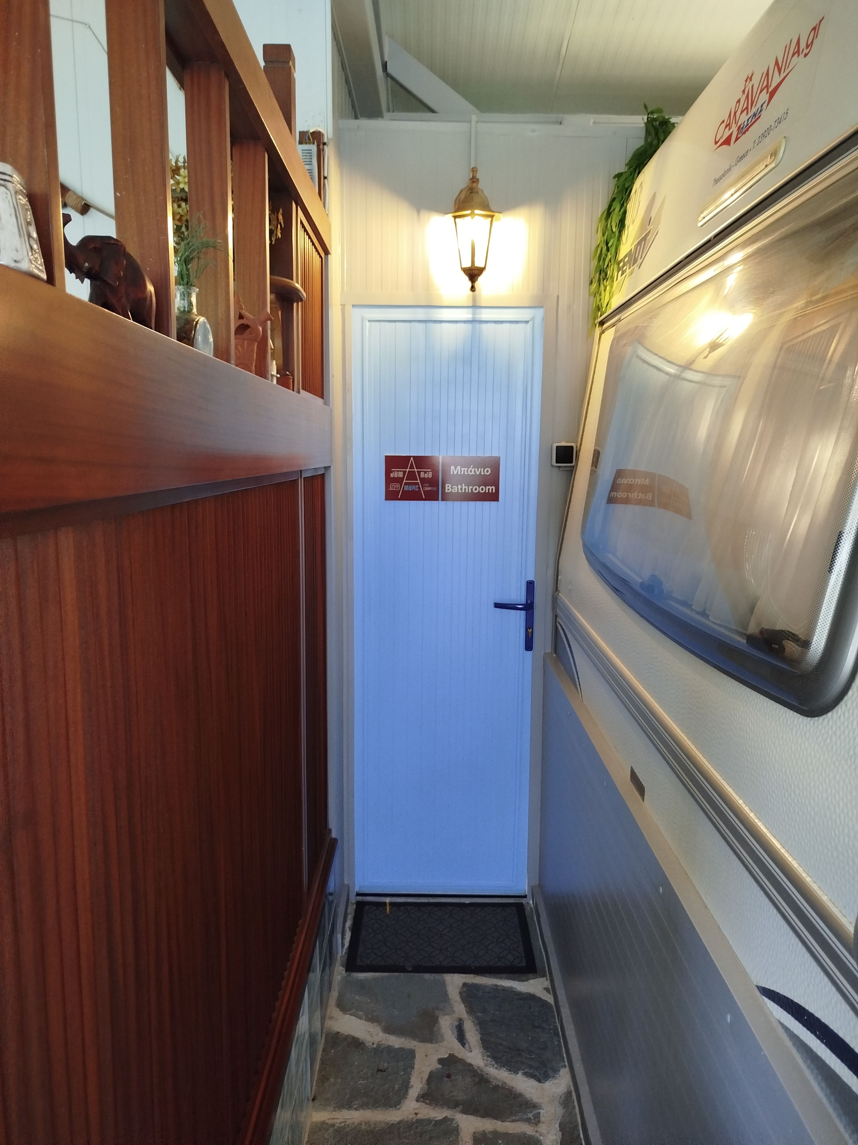 A narrow hallway leading to a bathroom with a sign indicating its location.