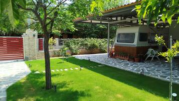 Jardí ben cuidat amb un pati pavimentat, una zona d'estar coberta i un vehicle a dins.