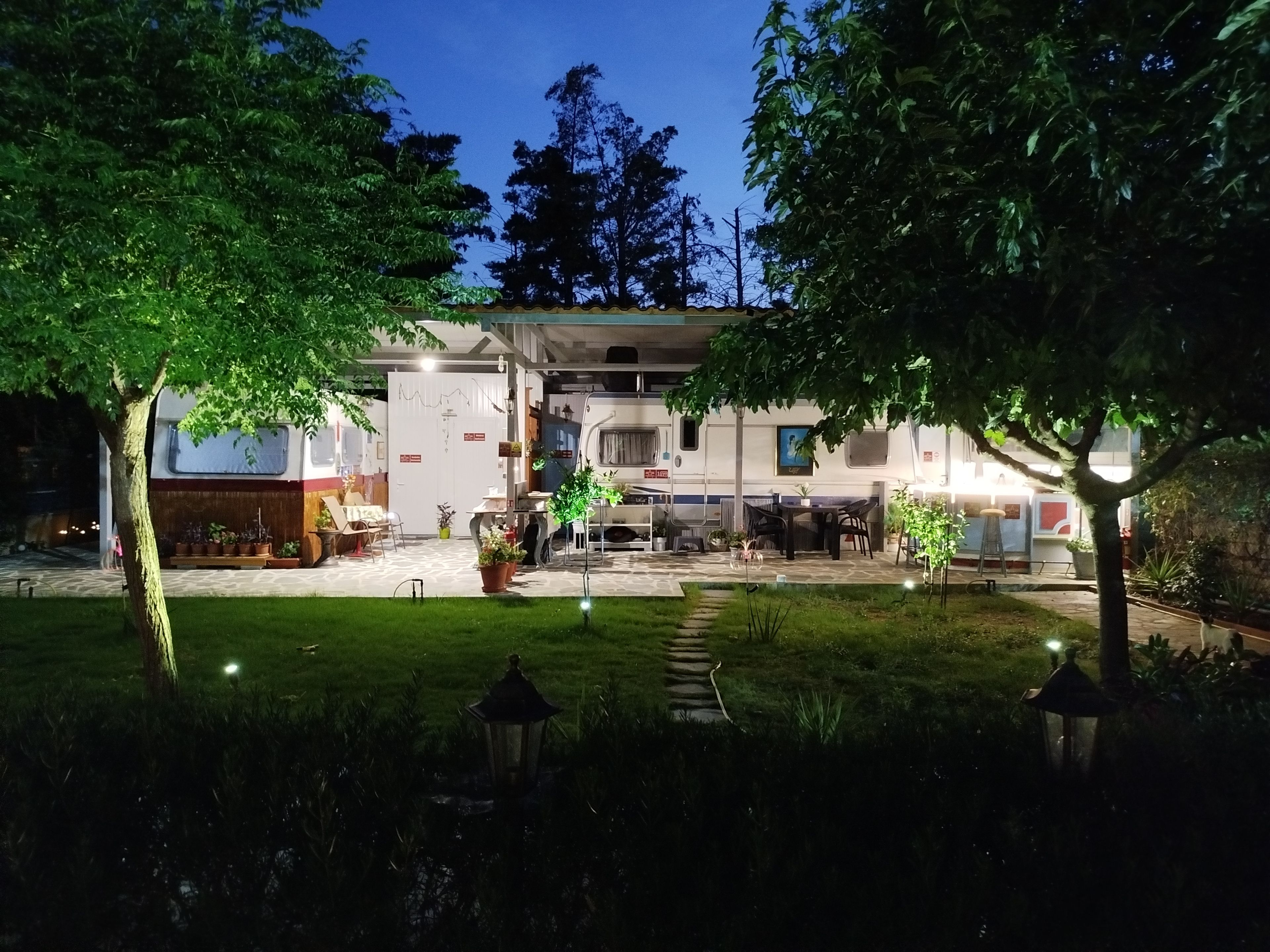 A hotel with a covered outdoor area, a dining table, and potted plants.