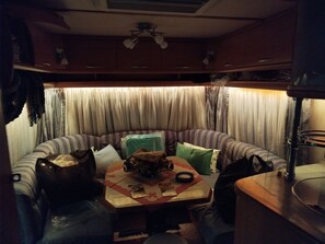 A compact living space with a kitchenette, a striped sofa, and a table with various items.