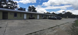 Un motel con una hilera de habitaciones, un estacionamiento y un edificio de techo plano.