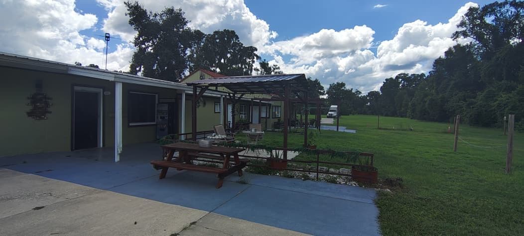 A building with a covered patio area, a picnic table, and a fenced outdoor space.