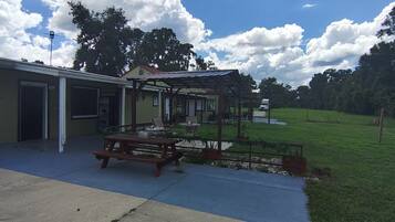 A building with a covered patio area, a picnic table, and a fenced outdoor space.