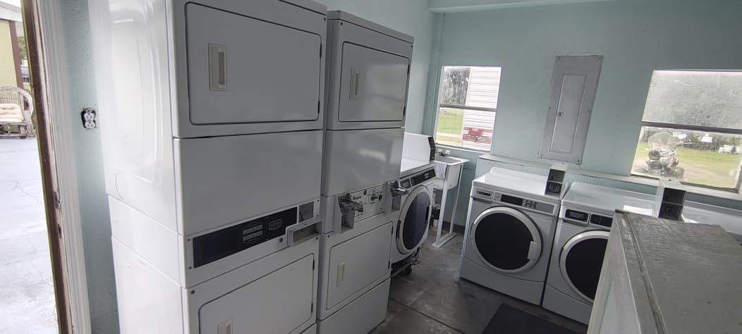 Une buanderie équipée d’une machine à laver et d’un sèche-linge superposés, d’une petite fenêtre et d’une porte donnant sur l’extérieur.