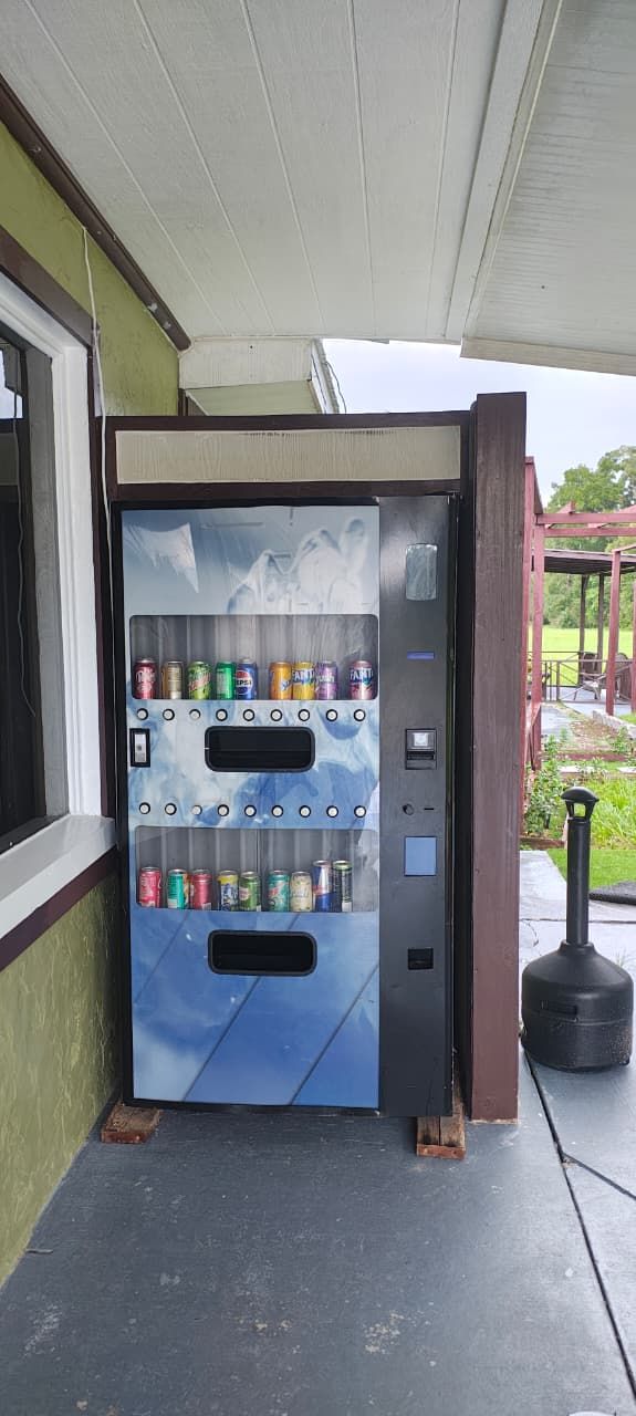 A vending machine with multiple beverage options, located outdoors near a building entrance.