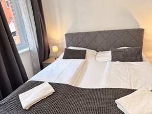 A neatly made bed with a grey headboard, white bedding, and a small bedside lamp. - Your Vienna Hideaway | Private Terrace & King Bed (Vienna)