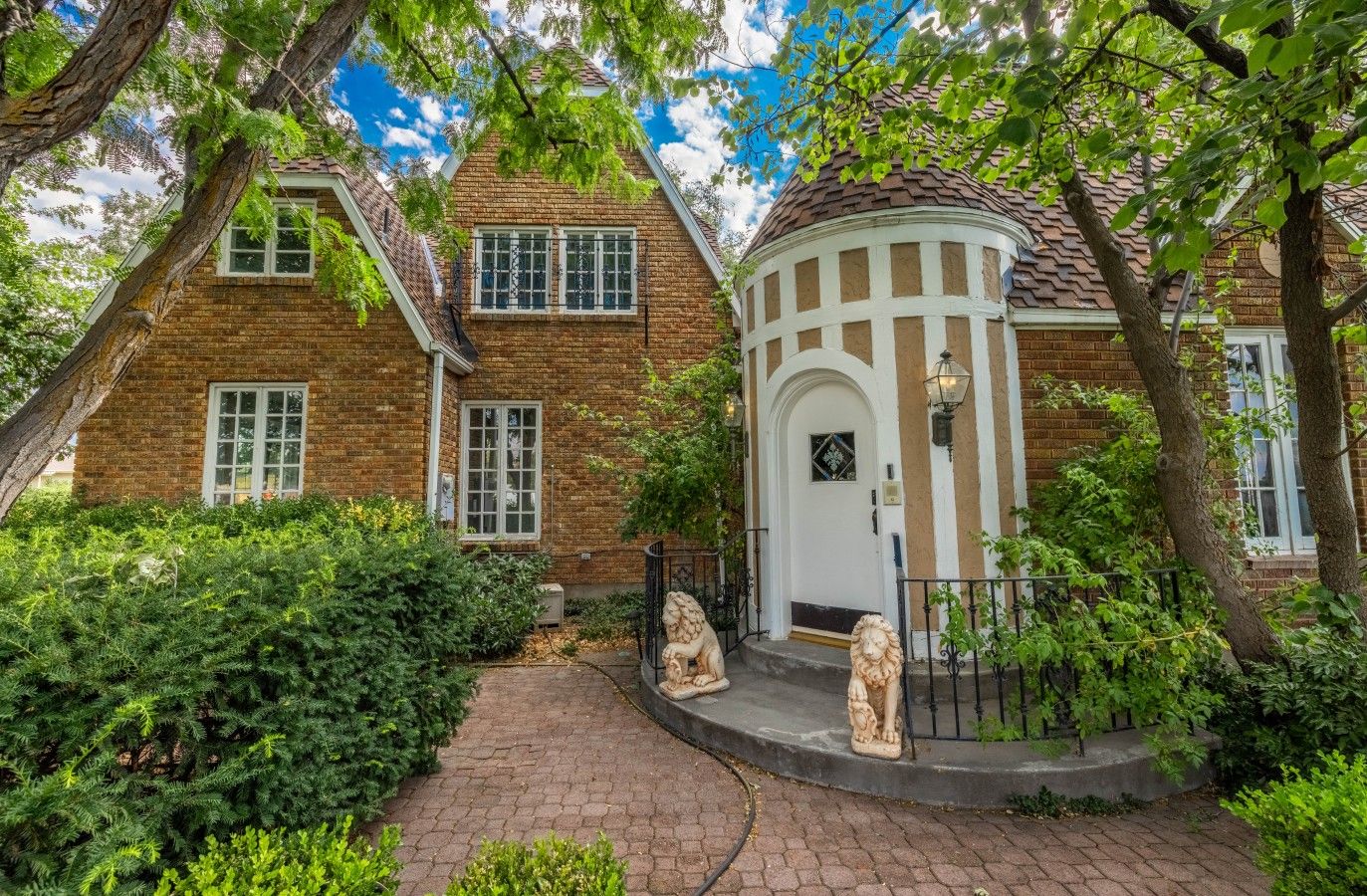 A brick house with a white door and a small porch with two lion statues.
