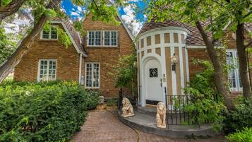 A brick house with a white door and a small porch with two lion statues.
