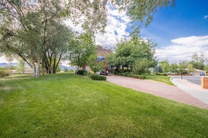 Una propietat residencial amb un jardí ben cuidat, una entrada de cotxes que condueix a una casa de maó, i un cel serè.