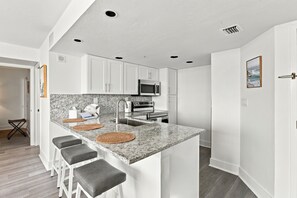 A modern kitchen with white cabinets, a granite countertop, and a built-in oven.