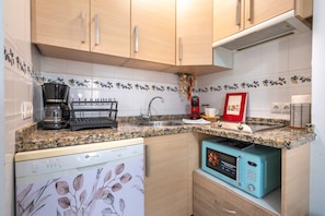 A compact kitchen with a dishwasher, coffee maker, and a retro-style microwave. - Beach days & tapas nights in the heart of Fuengirola (Fuengirola)