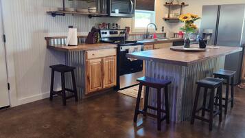 Una cocina con armarios de madera, un refrigerador de acero inoxidable y una barra con taburetes.