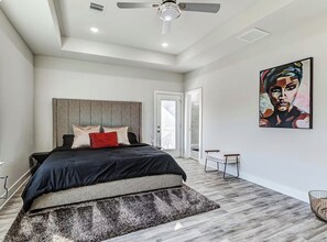 Ein modernes Schlafzimmer mit Bett, Deckenventilator und einem Gemälde an der Wand.