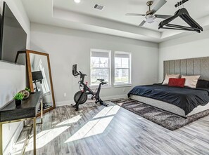 A modern bedroom with a bed, a desk, a mirror, and a ceiling fan. - Luxury Modern Stay Minutes from NRG & Med Center (Houston)
