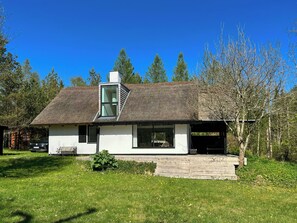 A modern house with a thatched roof, a large window, and a wooden deck. - Thatched holiday home in nature by the Gudenå (Ans)