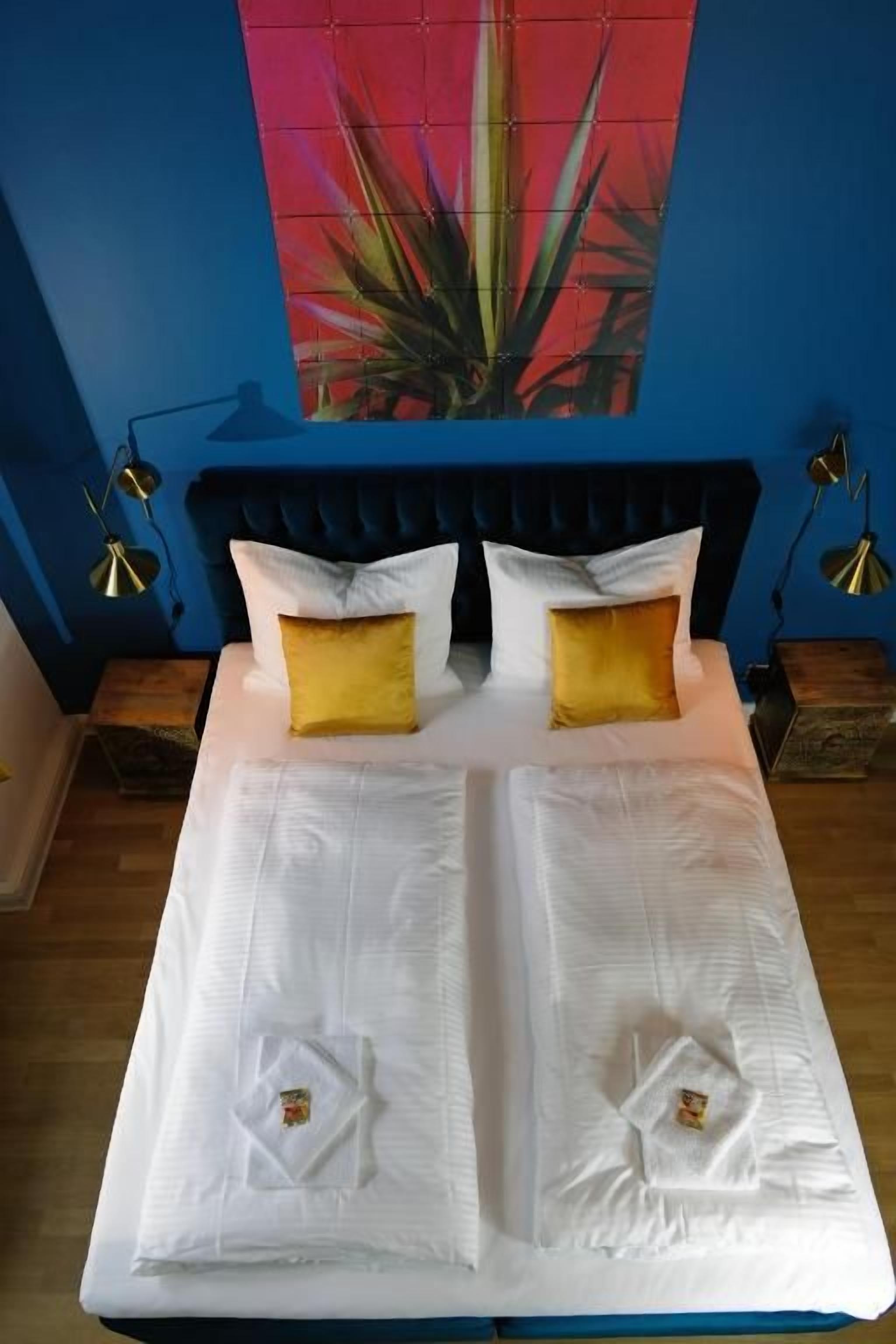 A bed with white linens, two yellow pillows, and a blue headboard.