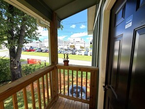 A wooden porch with a potted plant and a fan, overlooking a parking lot with cars and buildings. - Quiet 2BR Directly Across From Morristown-Hamblen Hospital (Morristown)