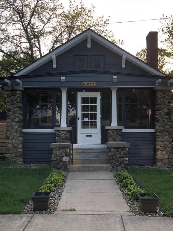 A small building with a stone facade, a white door, and a sign reading '121 N West'. - Charming 3-bedroom house with AC near the Mishawaka River Front (Mishawaka)