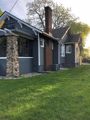 A two-story house with a stone pillar, a brick chimney, and a small attached garage. - Charming 3-bedroom house with AC near the Mishawaka River Front (Mishawaka)