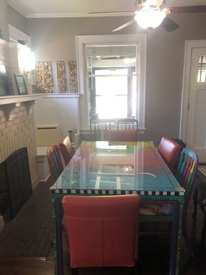 A dining area with a glass-top table, colorful chairs, a fireplace, and a ceiling fan. - Charming 3-bedroom house with AC near the Mishawaka River Front (Mishawaka)