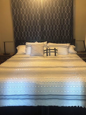 A bed with a patterned headboard, multiple pillows, and a striped bedspread. - Charming 3-bedroom house with AC near the Mishawaka River Front (Mishawaka)