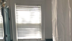 Un baño con un lavamanos blanco, un inodoro, una ventana con persianas y una cortina de ducha.