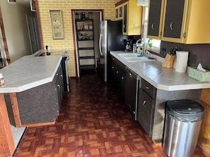 A kitchen with a herringbone wood floor, stainless steel appliances, and a built-in dishwasher.