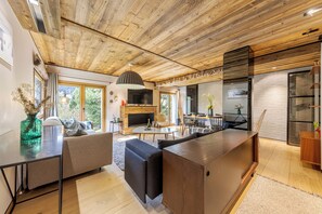 Une cuisine moderne dotée d’un îlot central, d’un plafond en bois et de grandes fenêtres.