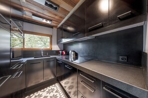 Une cuisine moderne dotée d’appareils électroménagers en acier inoxydable, d’une fenêtre donnant sur un espace verdoyant et d’un sol à motifs.