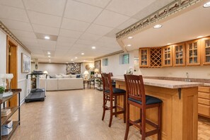 Una cocina amplia con armarios de madera, una isla central con taburetes de bar y un comedor con sofá y mesa.